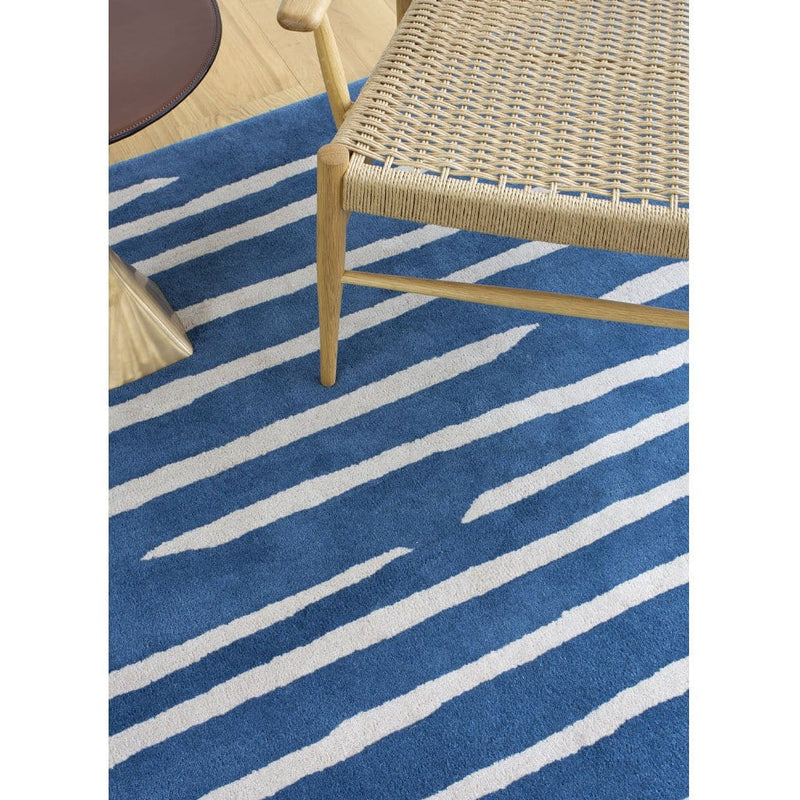 Island Blue Rug is an abstract lines patterned rug in two colours, blue and cream. The abstract lines pattern creates a circle shaped design within this rectangular wool rug. Rug detail close up.