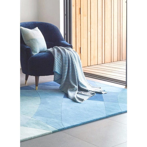 Rhythmic Tides Indigo Rug is an ocean themed round rug. It is designed in stunning blue-greens with a curved pattern to depict the ebb and flow of the tides. This is a contemporary coastal inspired rug, perfect for indoor living rooms, bedrooms or dining rooms. 
