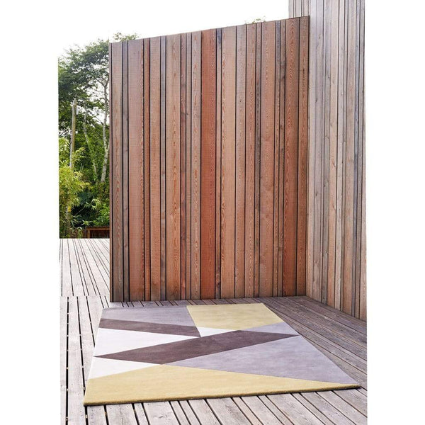 Sark Coupee Taupe Rug is a modern colour block rug with a bold geometric pattern in cream, grey, brown and gold. Handmade with high quality New Zealand wool. Pictured in architectural setting.