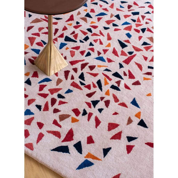 Lifestyle close-up image of Albecq Rug - a patterned modern rug with a colourful palette of reds, oranges and blues on a pink beige background. 